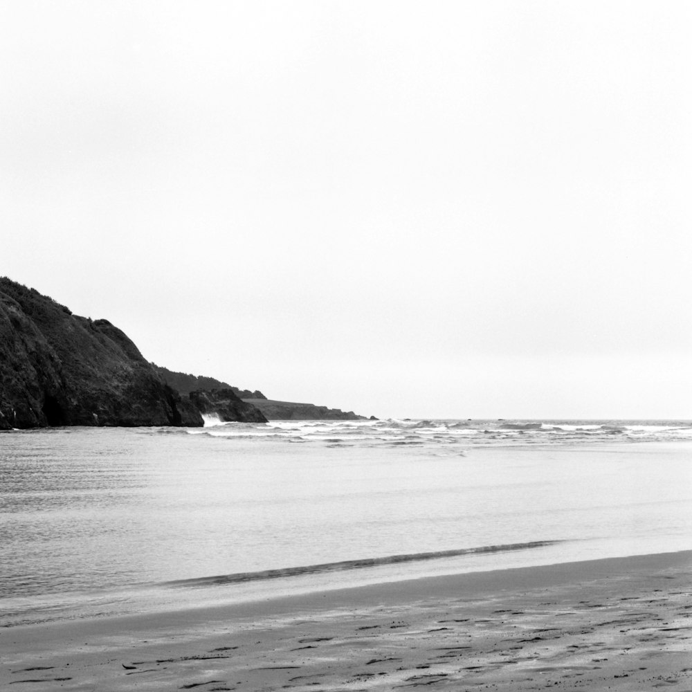 a black and white photo of a person walking on the beach