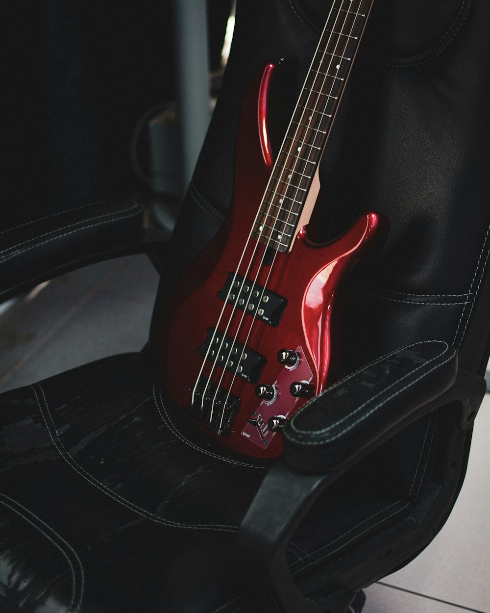 a red bass guitar sitting on top of a black chair