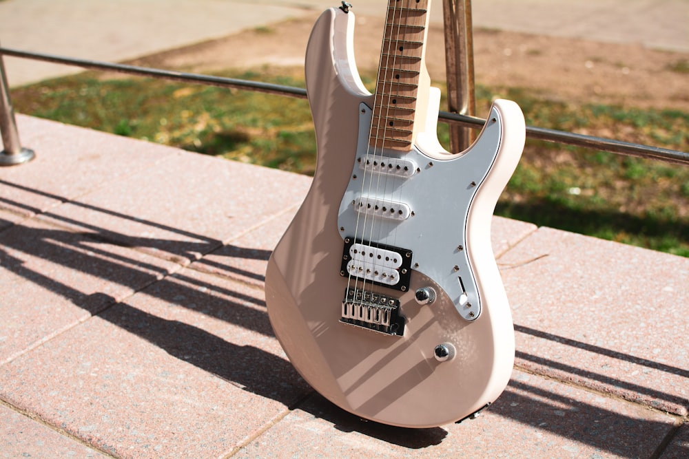 a white electric guitar sitting on top of a sidewalk