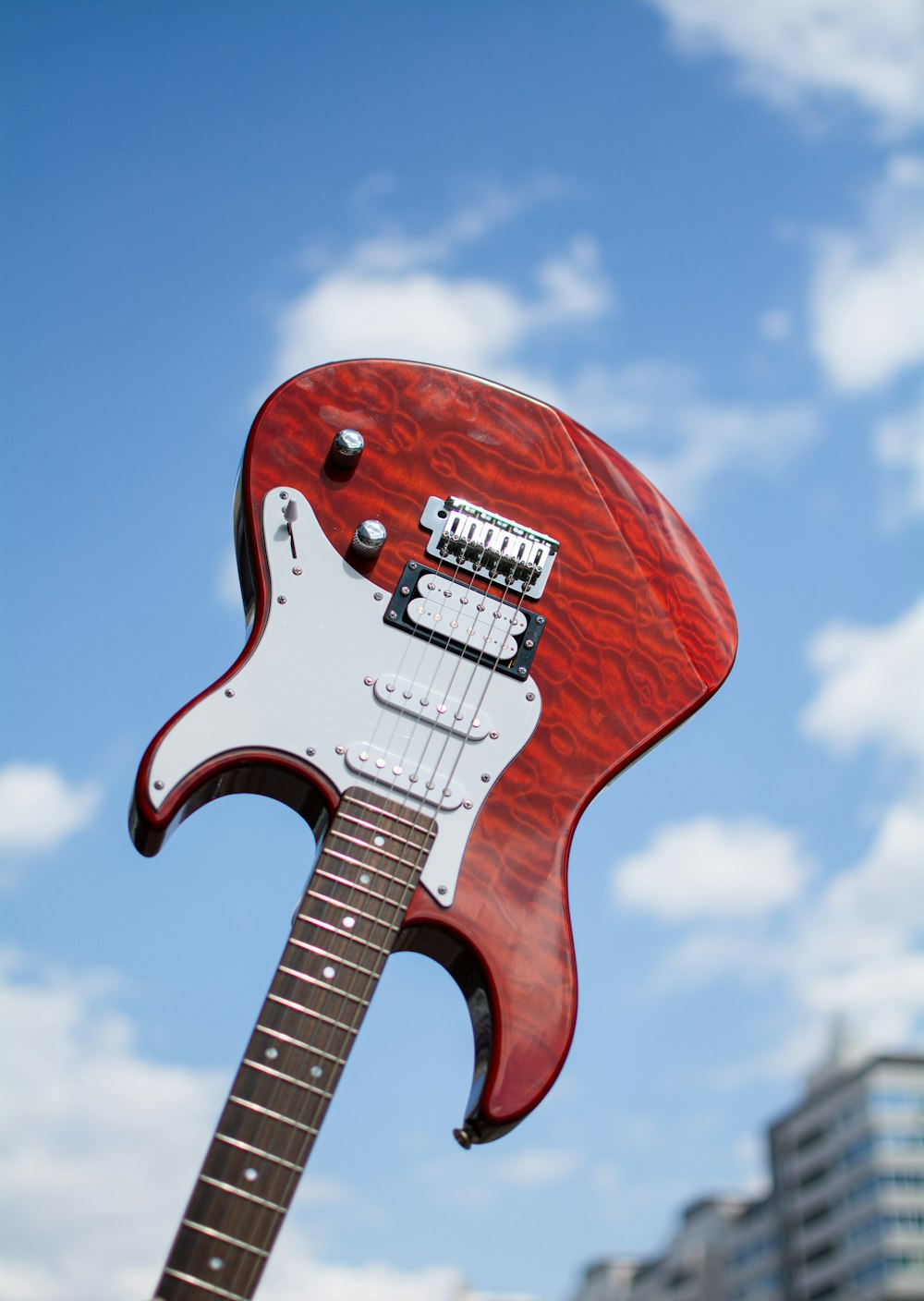 a red and white guitar with a sky in the background