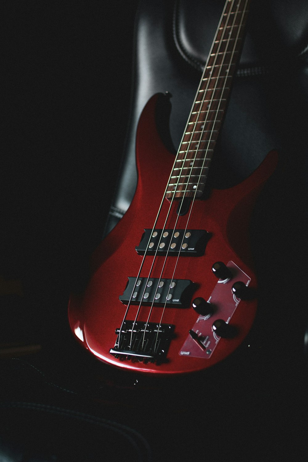 a red bass guitar sitting on top of a black chair