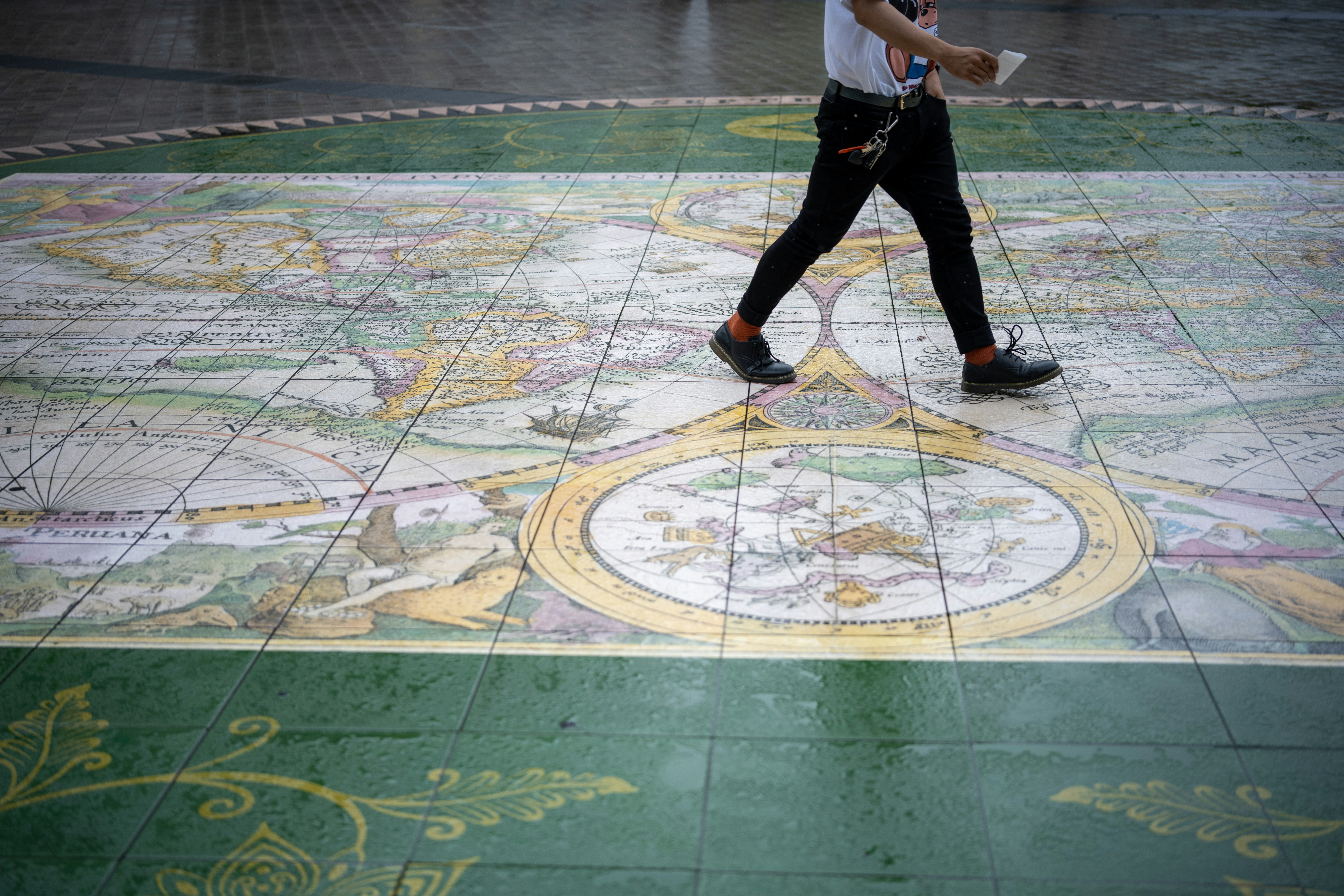 a man walking across a tiled floor with a umbrella