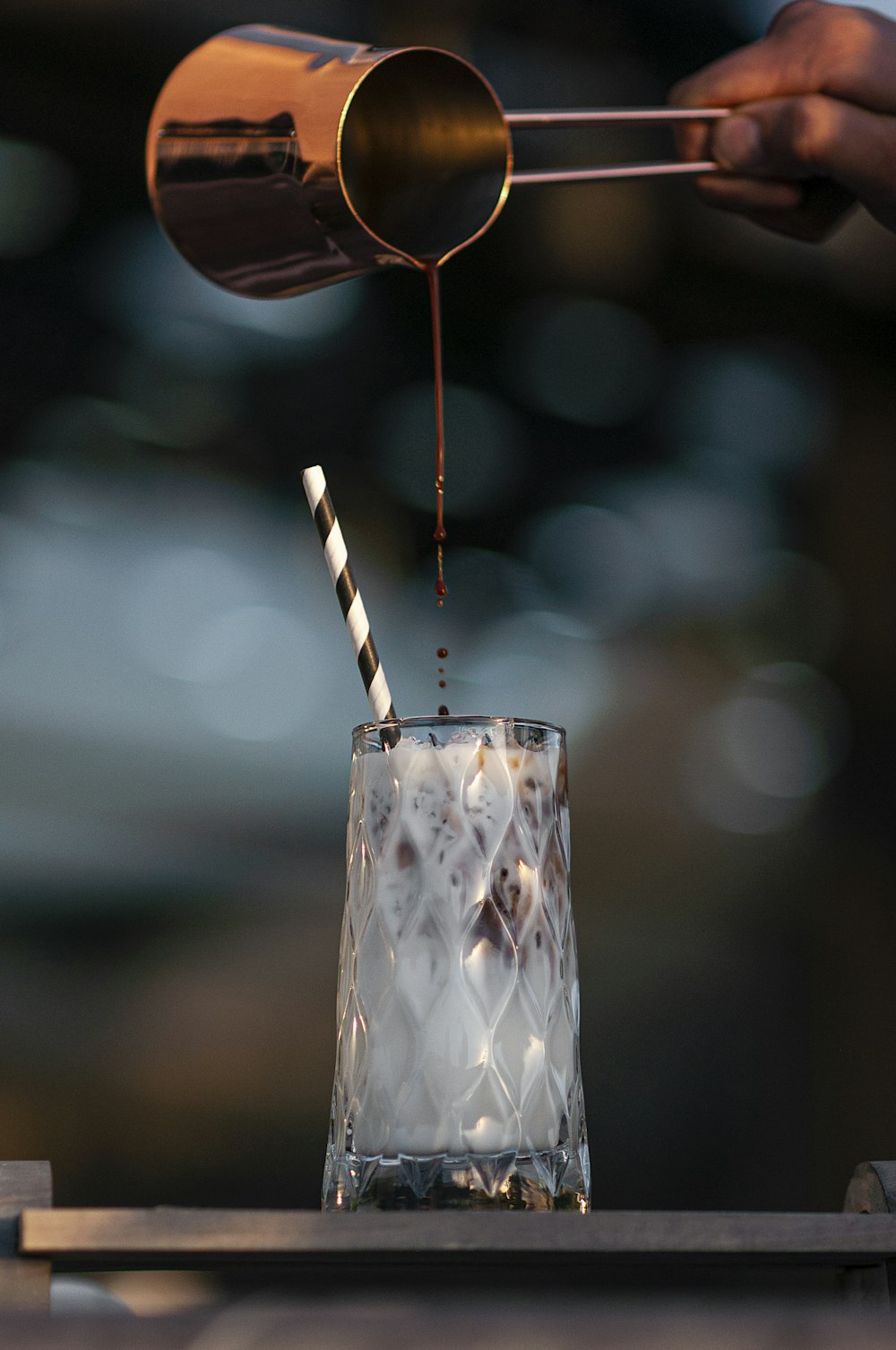 a person pouring a drink into a glass