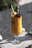 A tall glass of bright tropical smoothie garnished with a slice of pineapple and a straw.