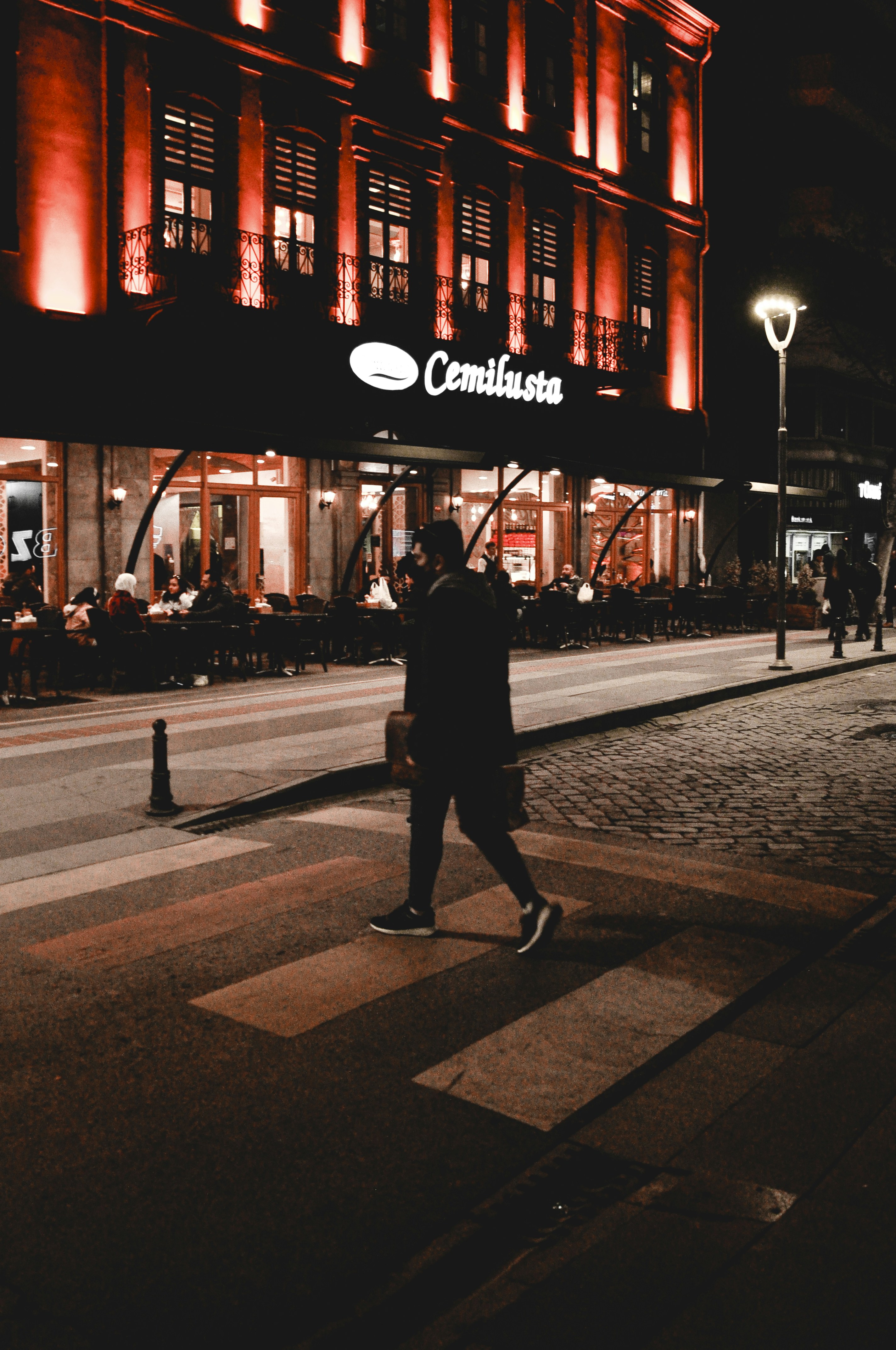 a man walking across a cross walk in front of a building