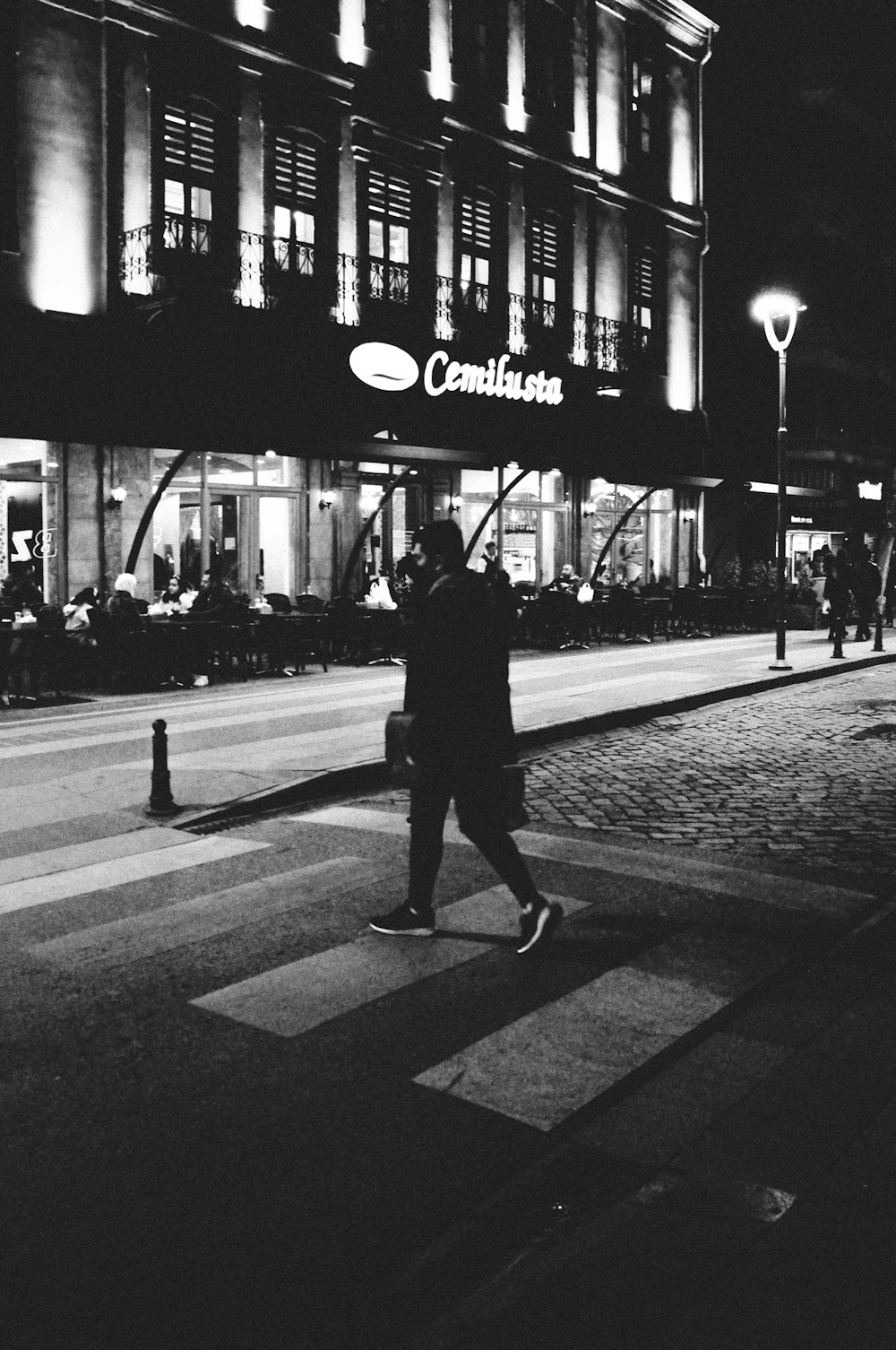 a man walking across a street at night
