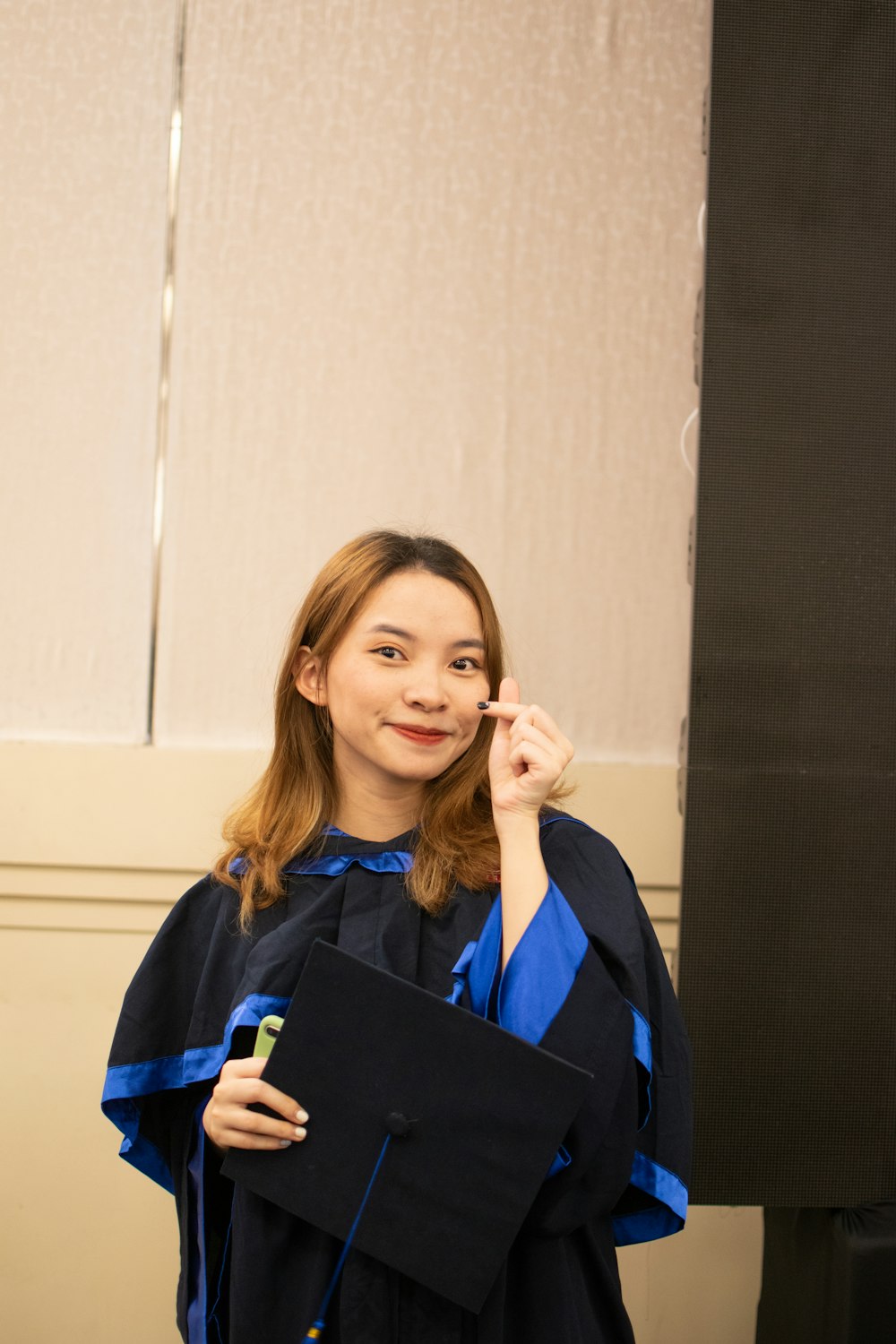 a woman in a graduation gown holding a cell phone