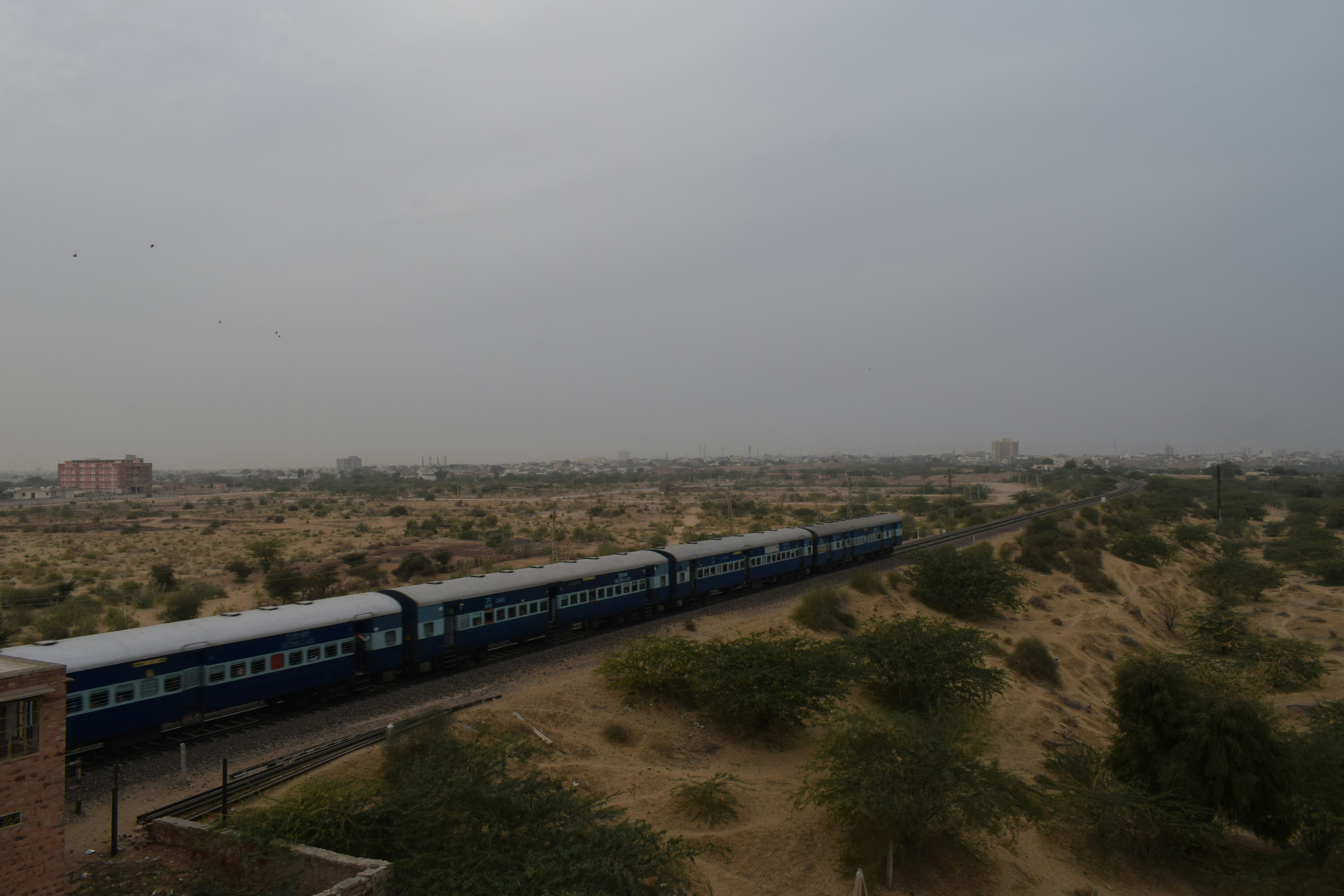 a train traveling through a rural countryside under a cloudy sky