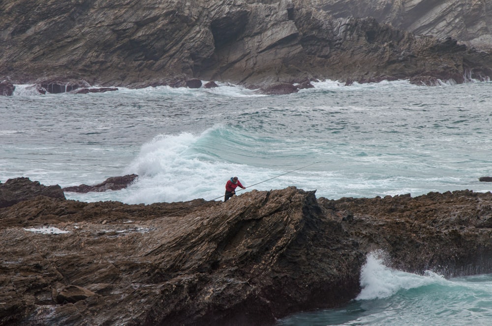 a person standing on a rock near the ocean