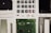 A collection of disassembled electronic components including buttons, a circuit board, a screen, wires, screws, and other small parts, neatly arranged on a white surface.