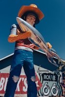 a statue of a cowboy holding a surfboard