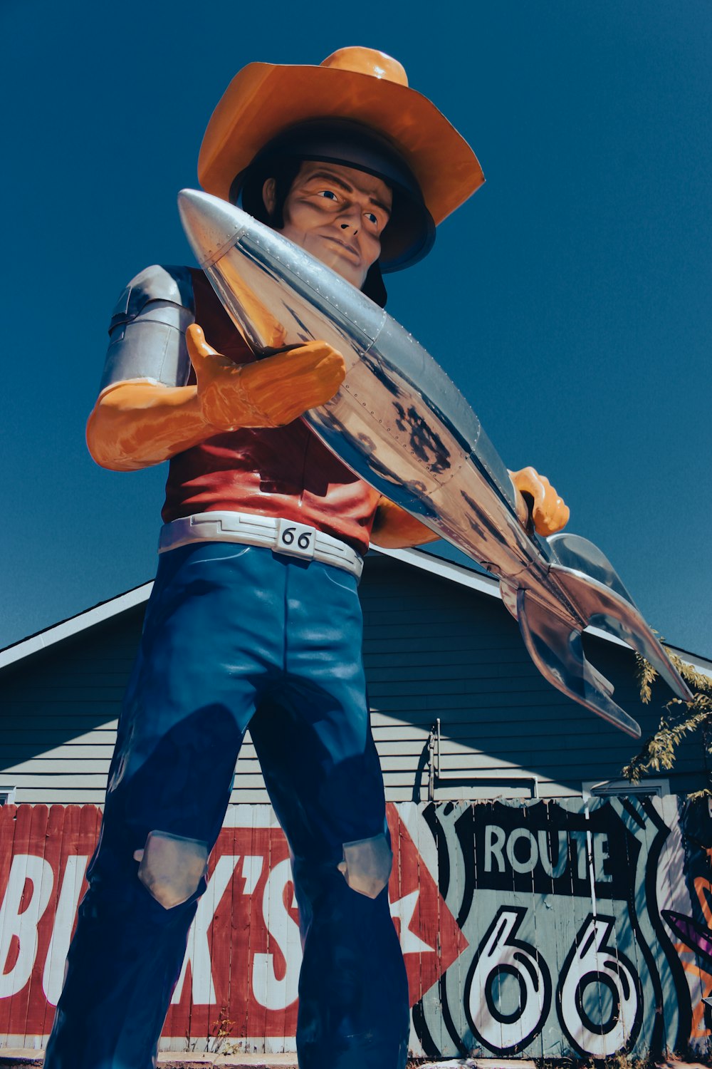 a statue of a cowboy holding a surfboard