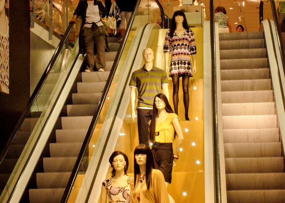 a group of mannequins are on an escalator