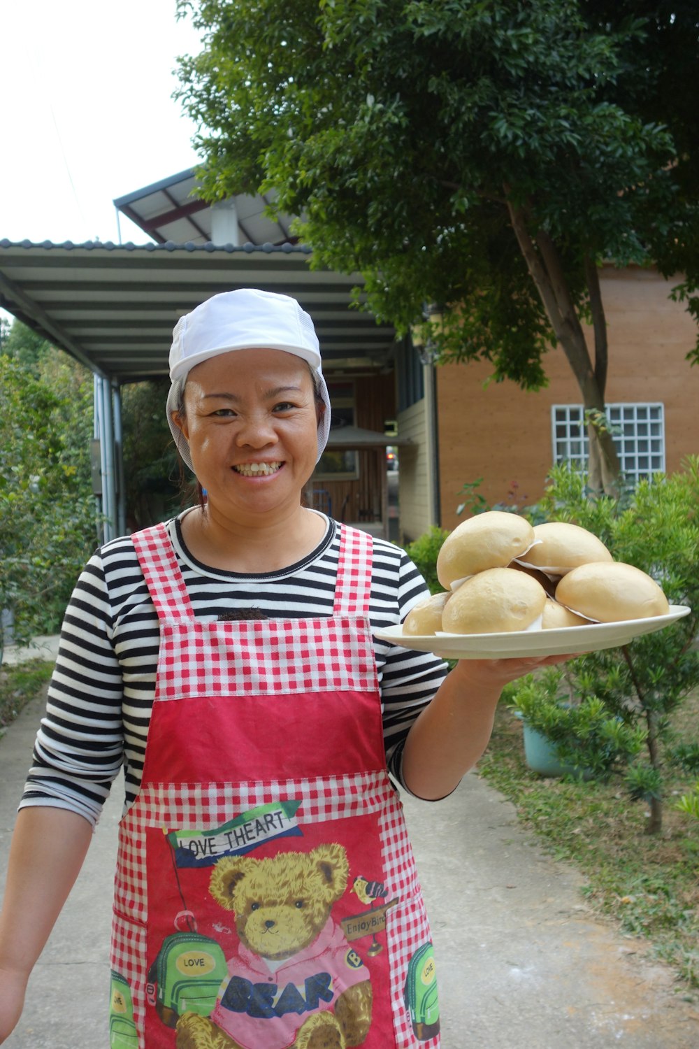 a woman in an apron holding a plate of donuts