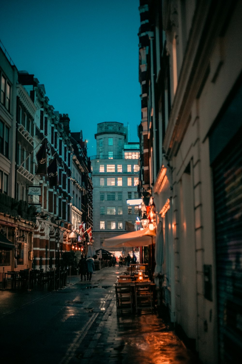 a city street at night with people walking on the sidewalk