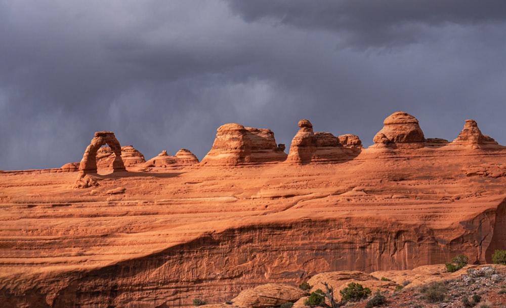 a large rock formation in the desert under a cloudy sky