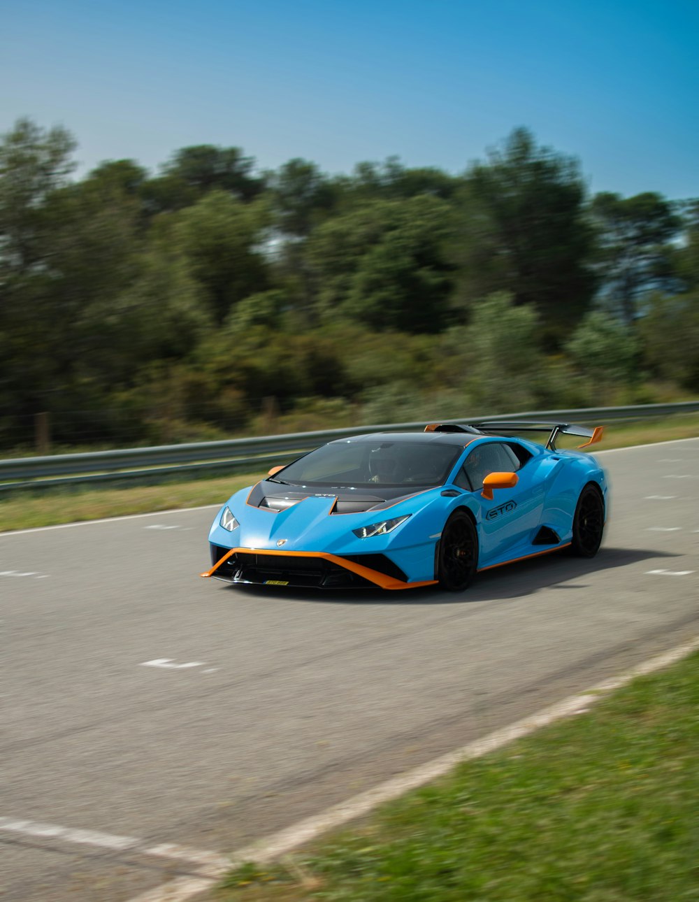 a blue and orange sports car driving down a road