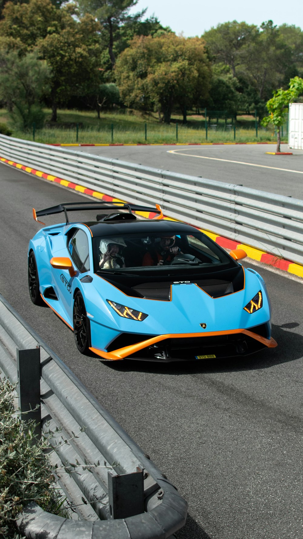 a blue and orange sports car driving down a race track