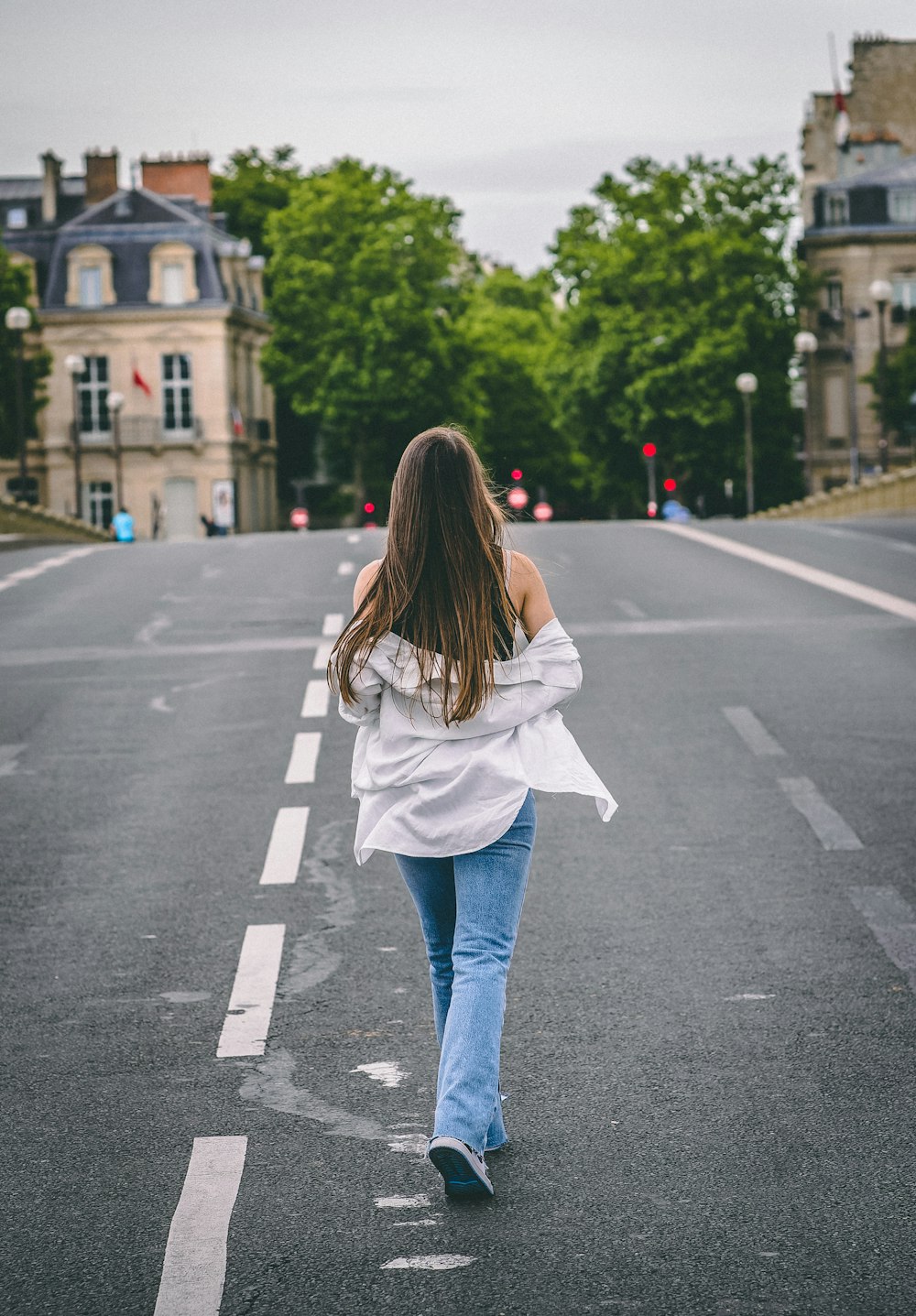 a woman walking down the middle of a street