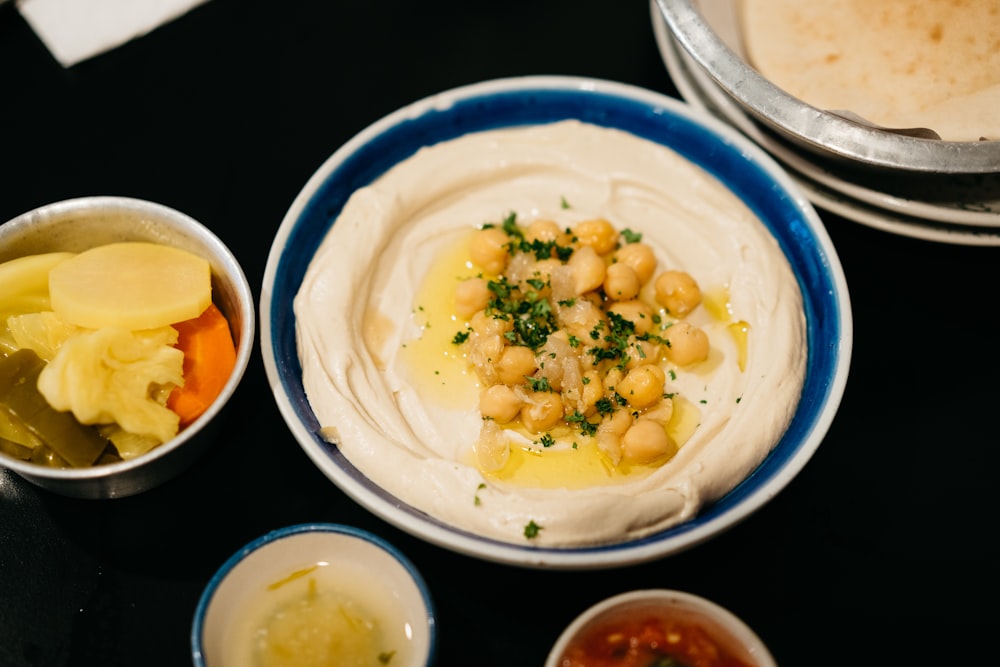 a table topped with bowls of food and a plate of hummus