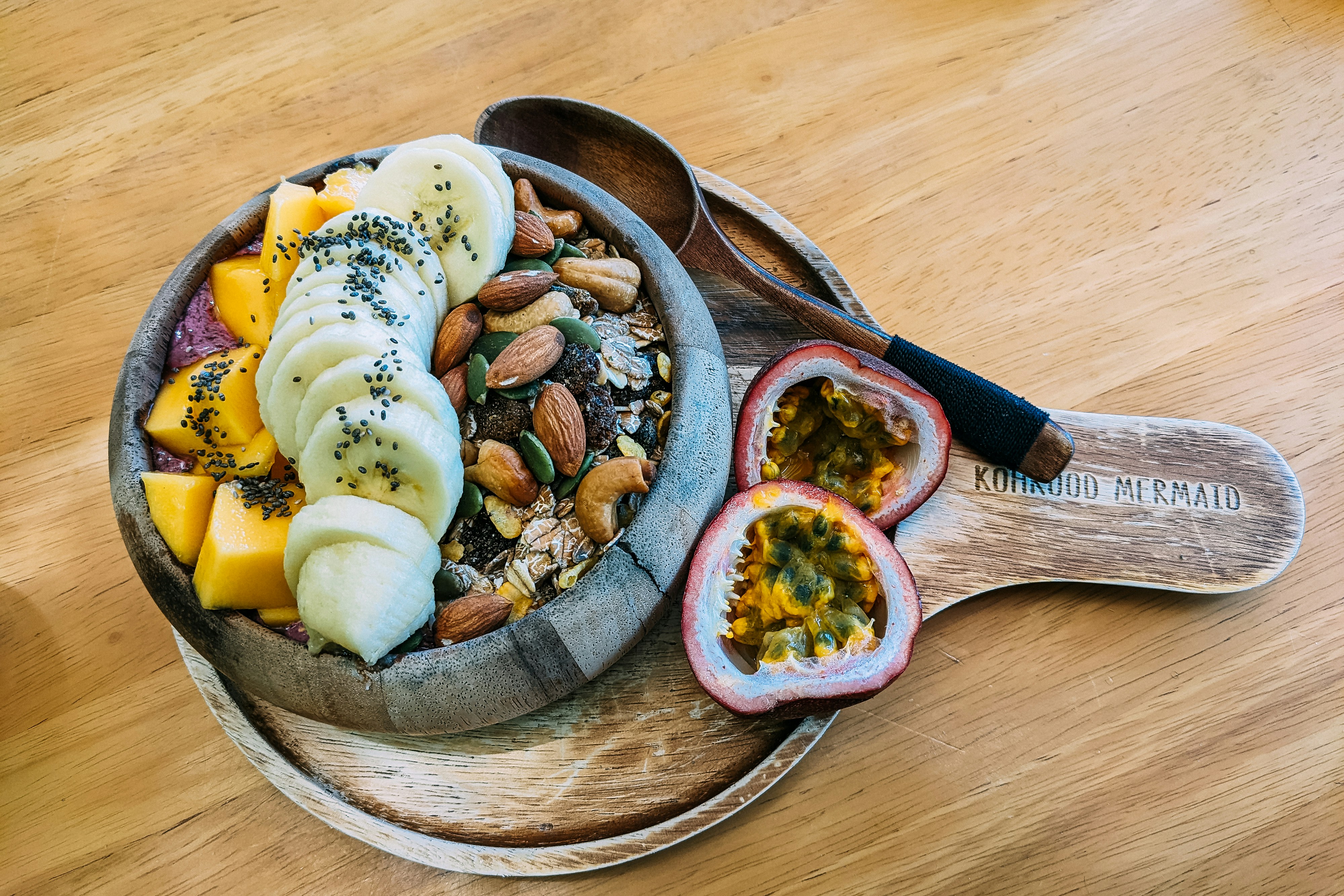 Wooden bowl with fruit, nuts and passionfruit