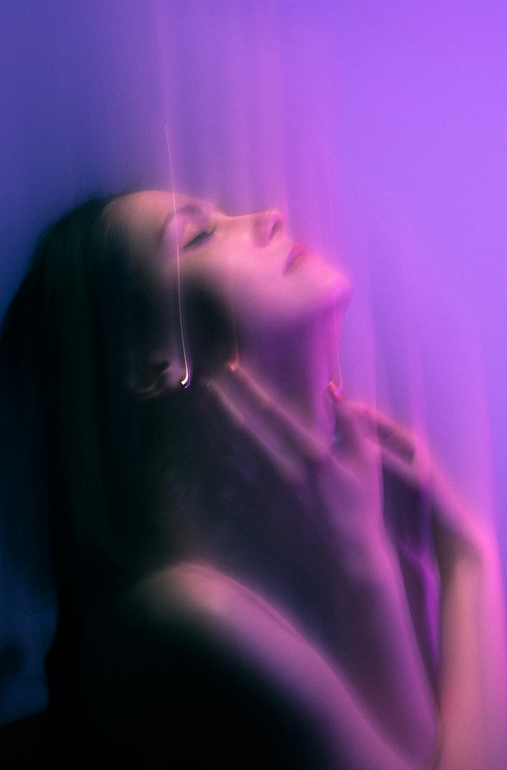 Une femme les yeux fermés debout devant un fond violet