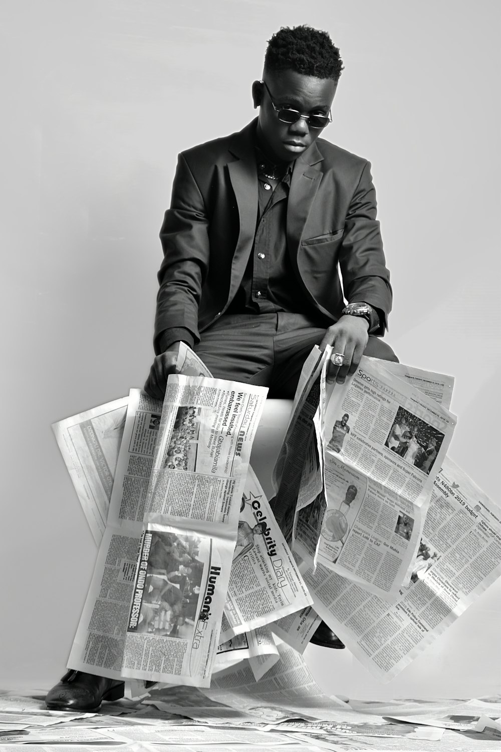 a man sitting on top of a pile of newspapers