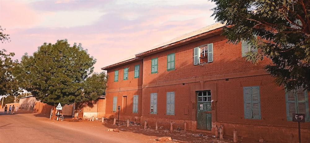 a red brick building with green shutters on the windows