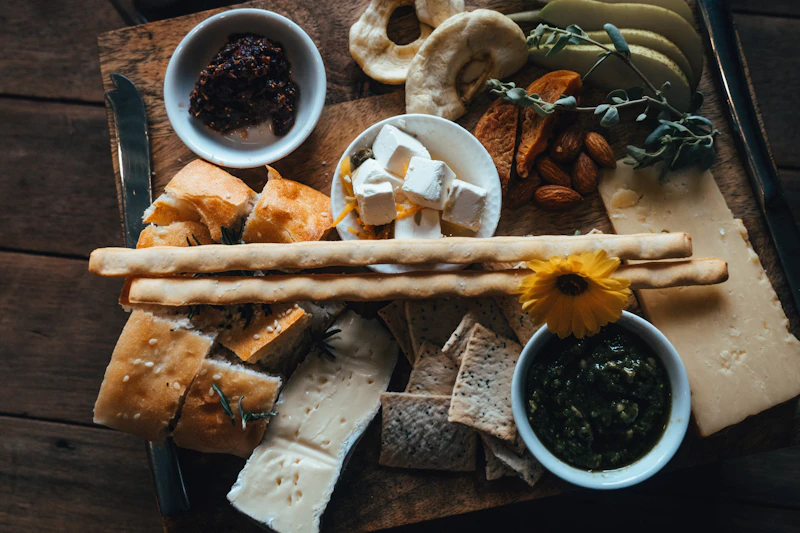 wooden table covered with breads, dips and snack bowls