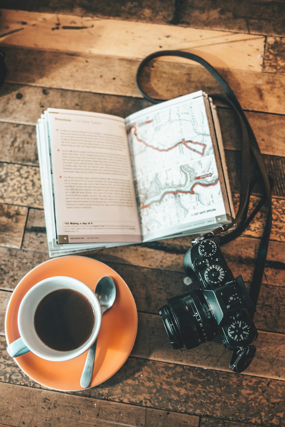 uma câmera, um livro e uma xícara de café em uma mesa