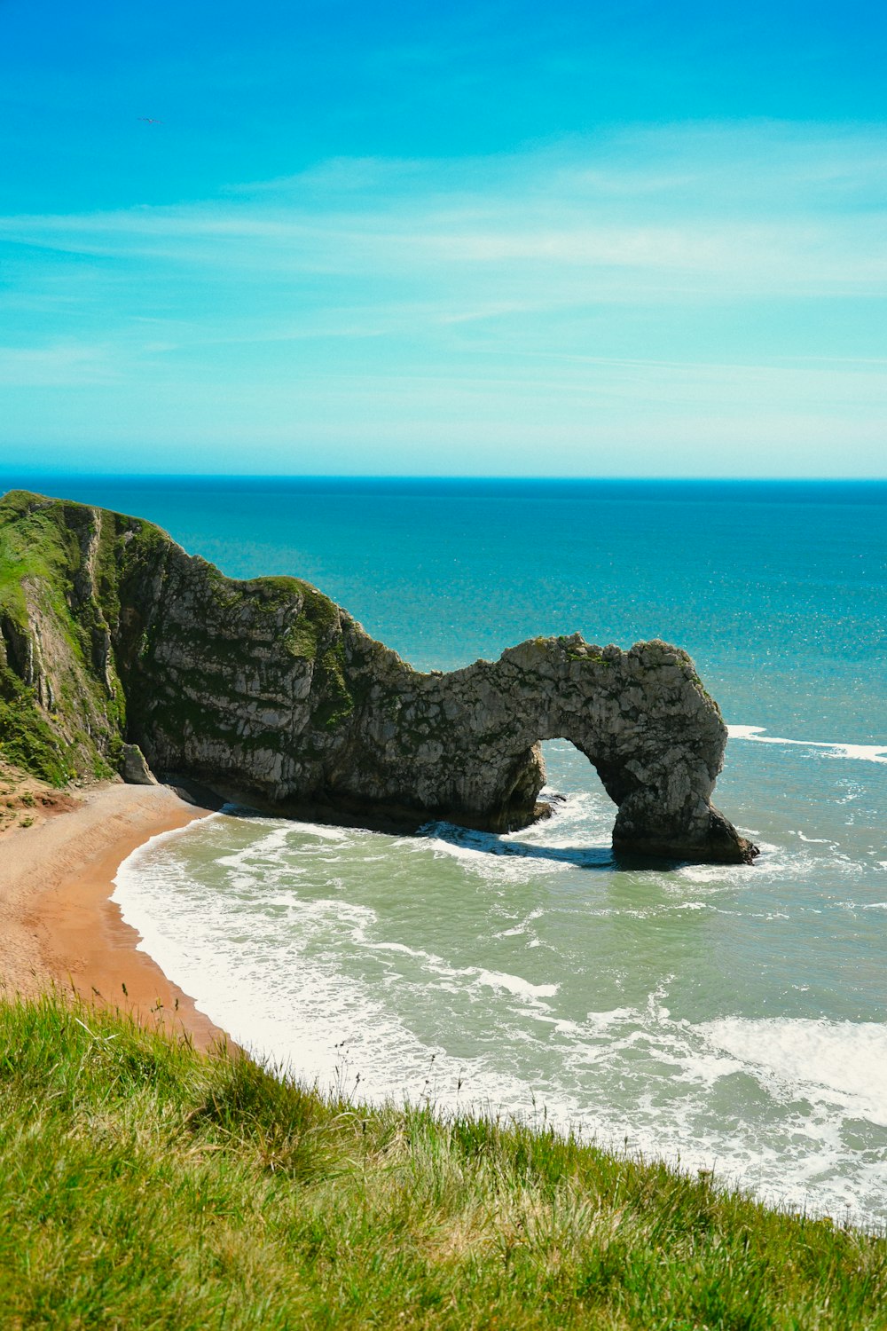 a large rock formation sitting on top of a beach next to the ocean