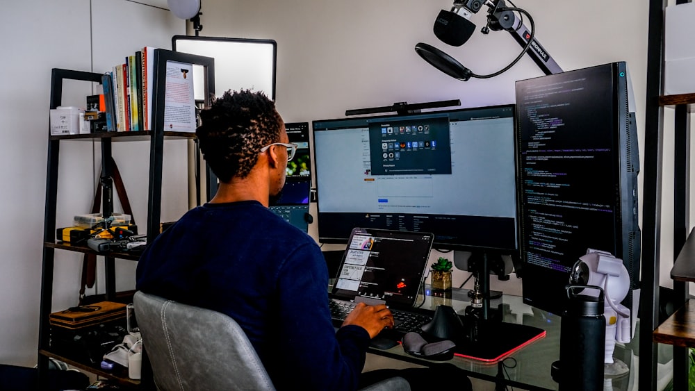 a man sitting in front of a computer monitor