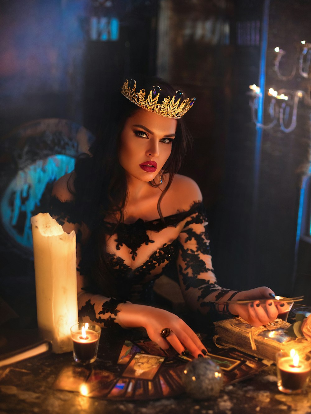 a woman in a crown sitting at a table with candles