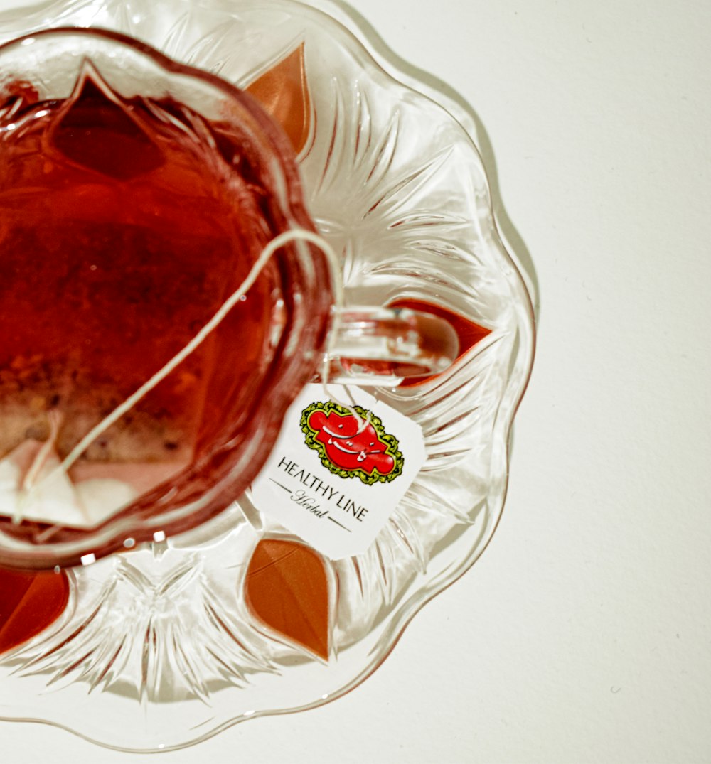 a glass bowl filled with liquid next to a bottle of ketchup