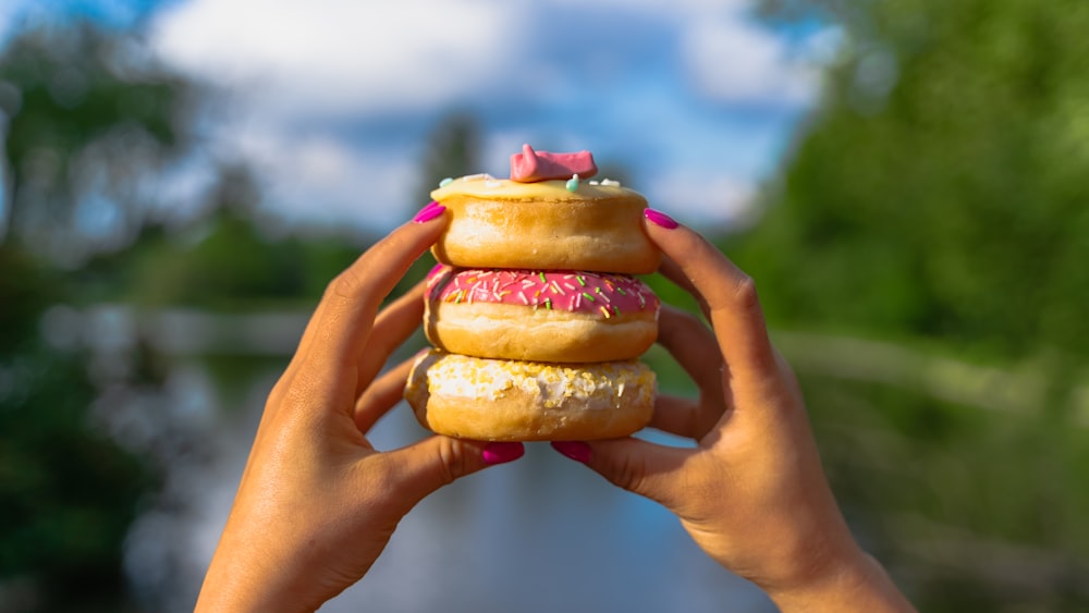 a woman holding a stack of donuts in front of her face