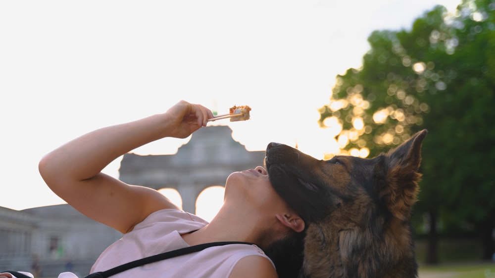 a woman laying on the ground with a dog and a piece of food in her