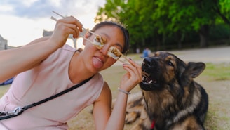 a woman eating food while sitting next to a dog