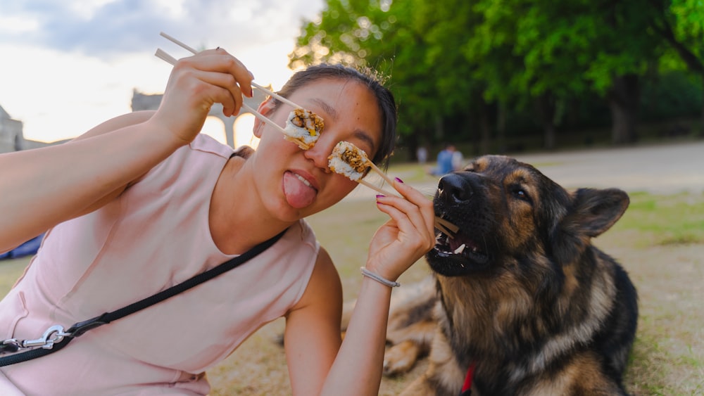 a woman eating food while sitting next to a dog