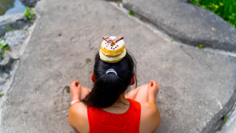 a little girl sitting on the ground with her hair in a bun