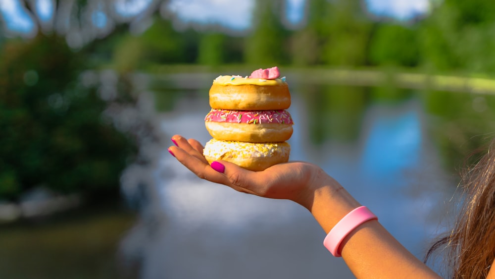 a woman holding a stack of donuts in her hand