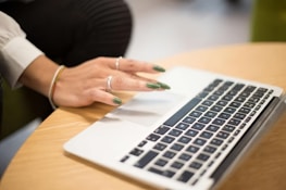 a woman sitting at a table using a laptop computer