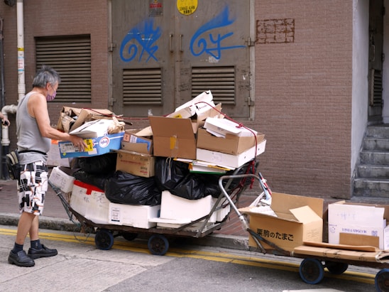 Two movers carrying boxes, a woman cleaning an apartment, and a pile of garbage bags.