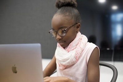 A young girl learning computer skills in a bright classroom setting.