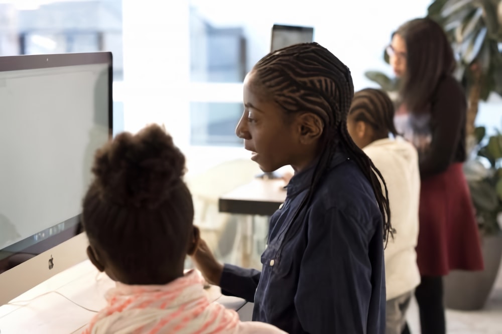 a little girl is playing with a computer monitor