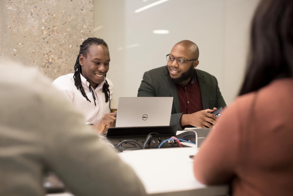 a group of people sitting around a laptop computer