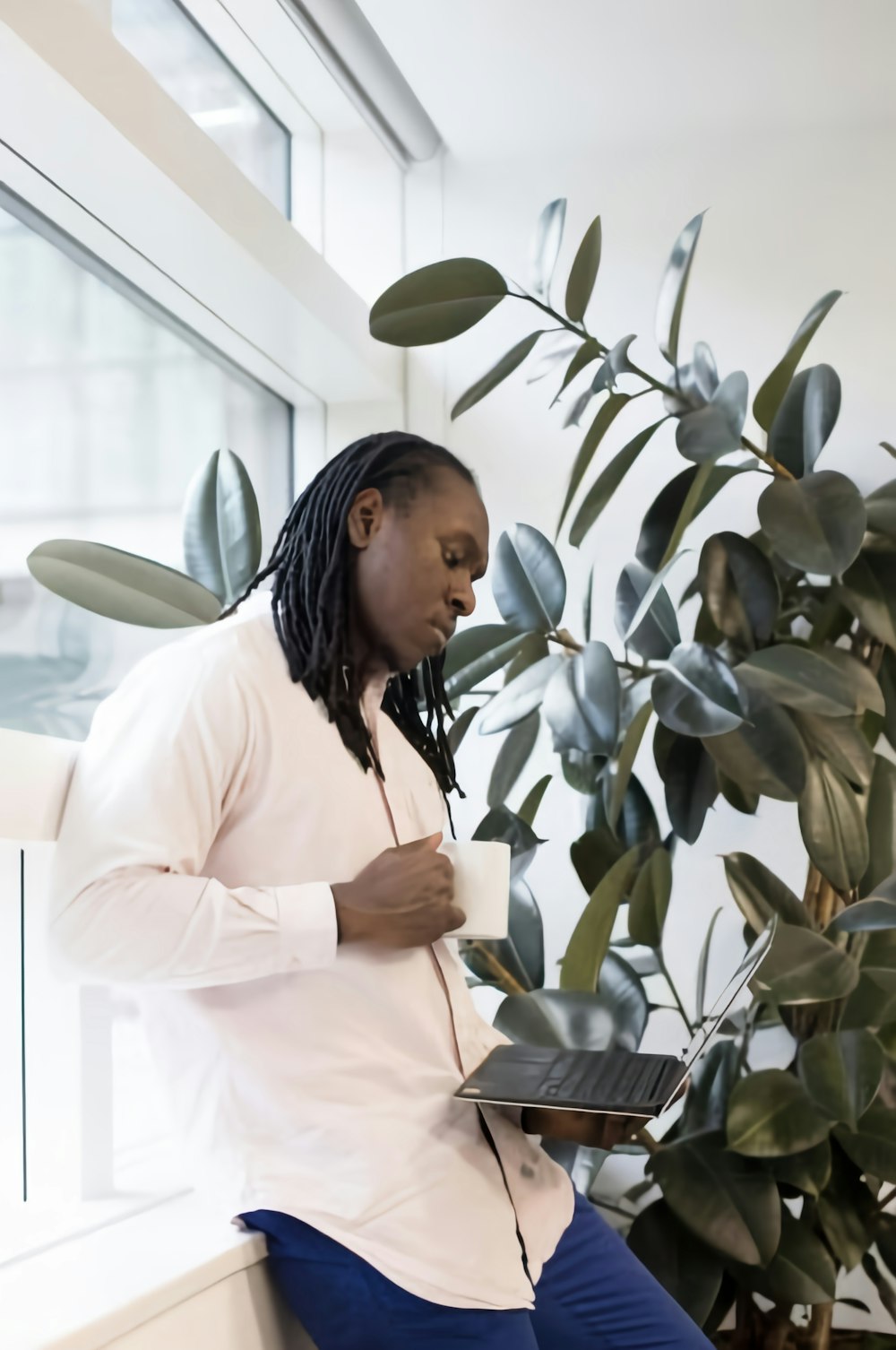 a man sitting on a window sill using a laptop