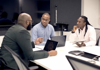 a group of people sitting around a table with laptops