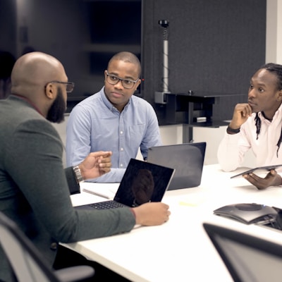 a group of people sitting around a table with laptops