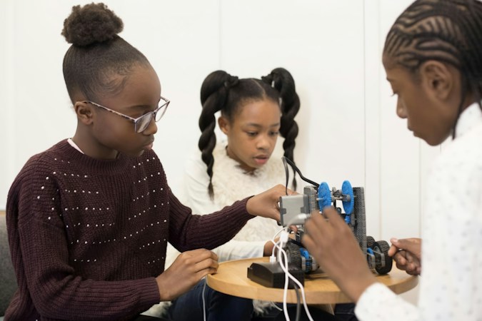 Two middle school girls working together on a hands-on STEM project at a classroom table