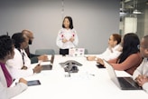 a group of people sitting around a table with laptops